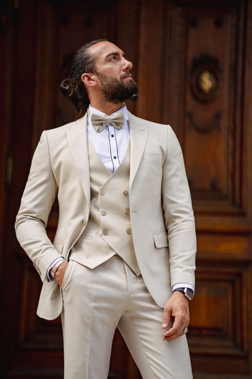 A man dressed in a Birch Beige Tuxedo Suit with a bow tie