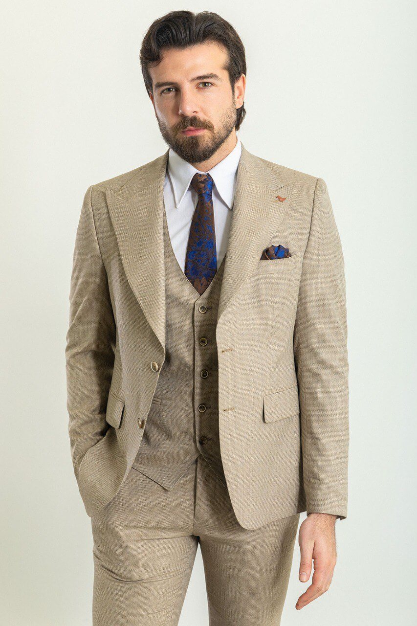 Man in a plaid beige 3-piece suit with a blue tie and pocket square.