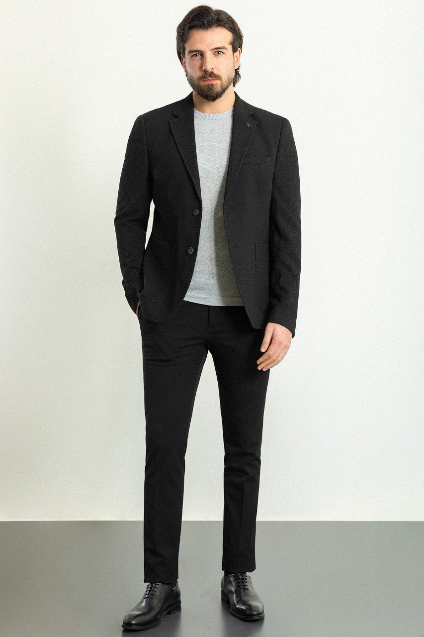 Man wearing a black blazer paired with a light grey sweater.