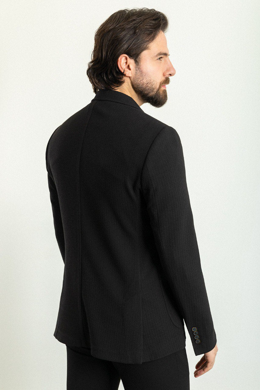 Man wearing a black blazer paired with a light grey sweater.
