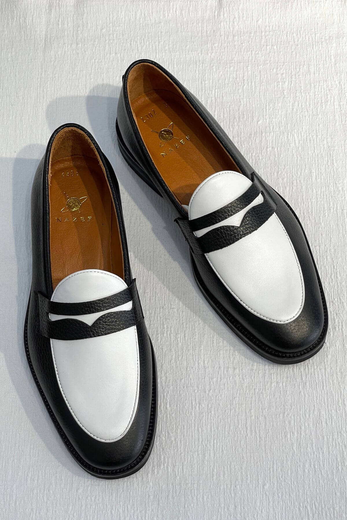 Bicolor Leather Penny Loafers in Black and White on a light gray background