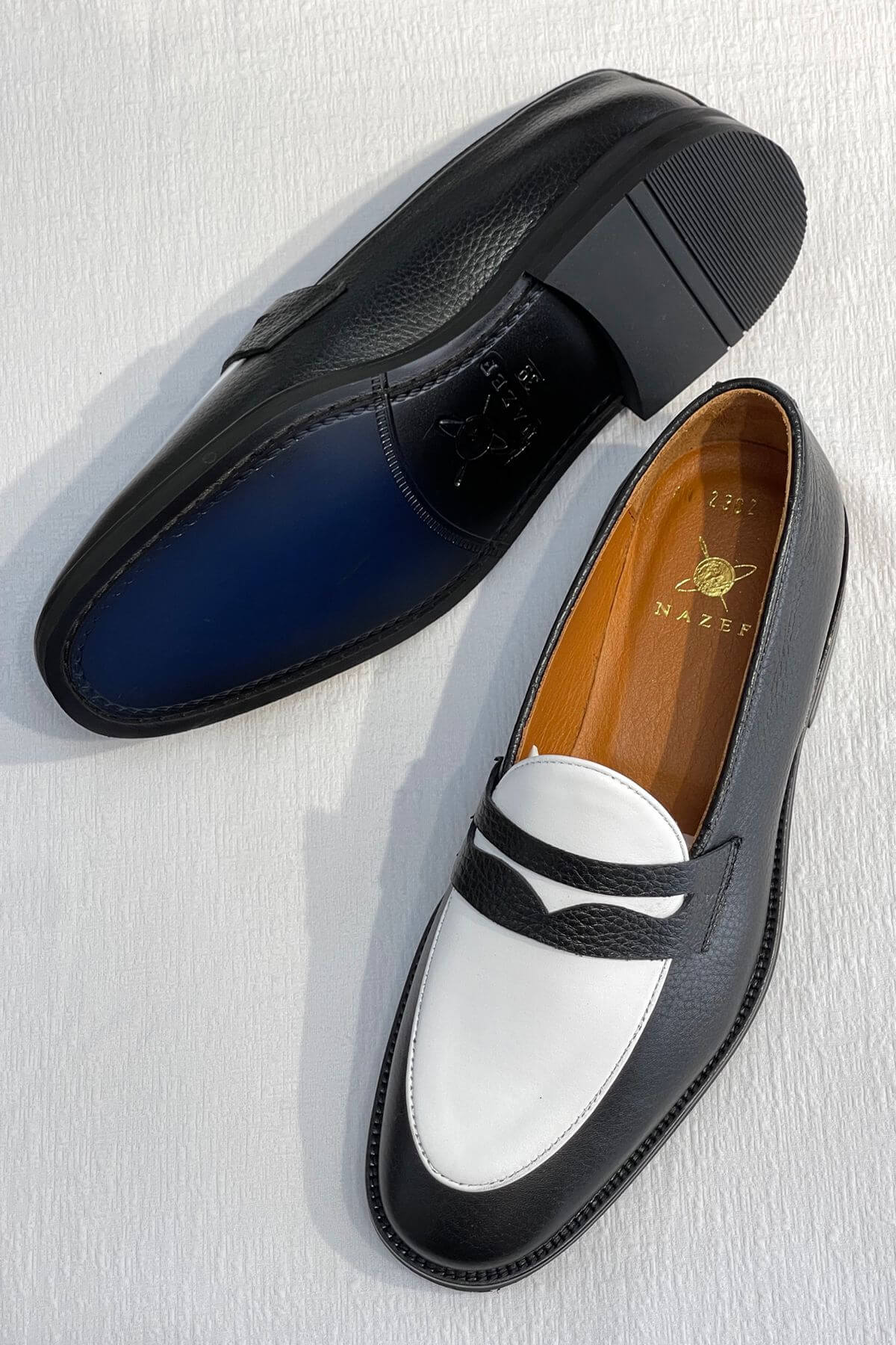 Bicolor Leather Penny Loafers in Black and White with a brand logo on a light gray background