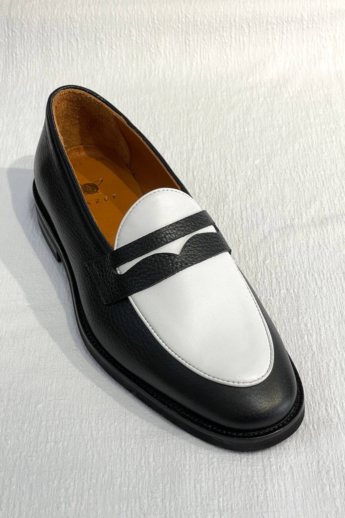 Black and white loafer shoe on a light gray background