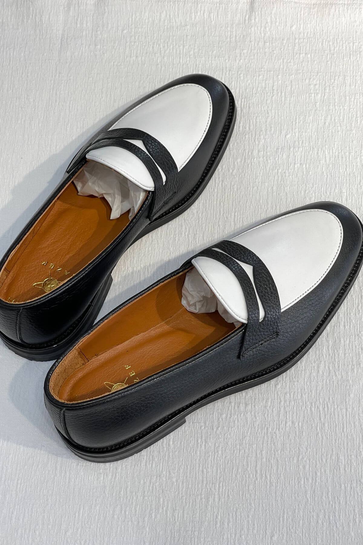 Pair of Bicolor Leather Penny Loafers in Black and White on a light gray background