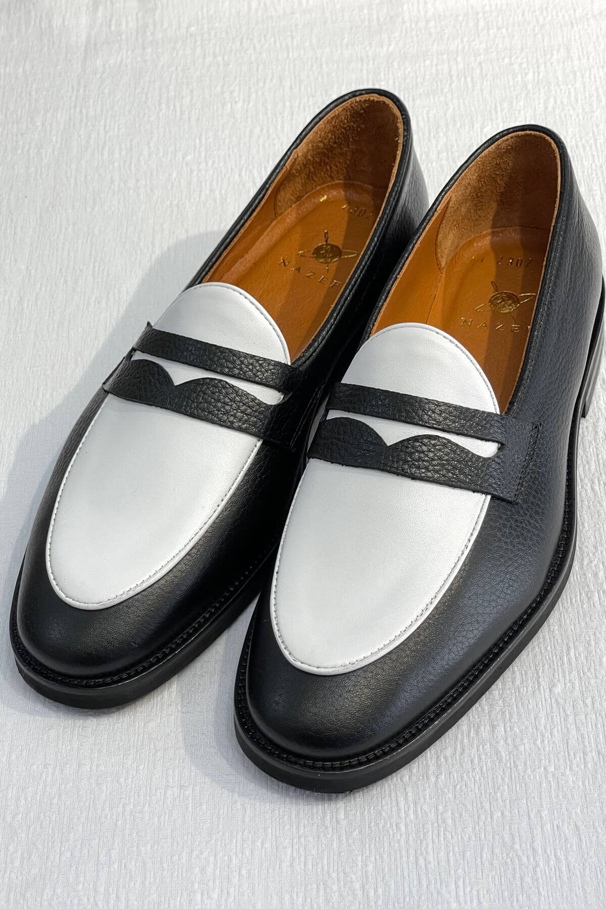 Pair of Bicolor Leather Penny Loafers in Black and White on a light gray background
