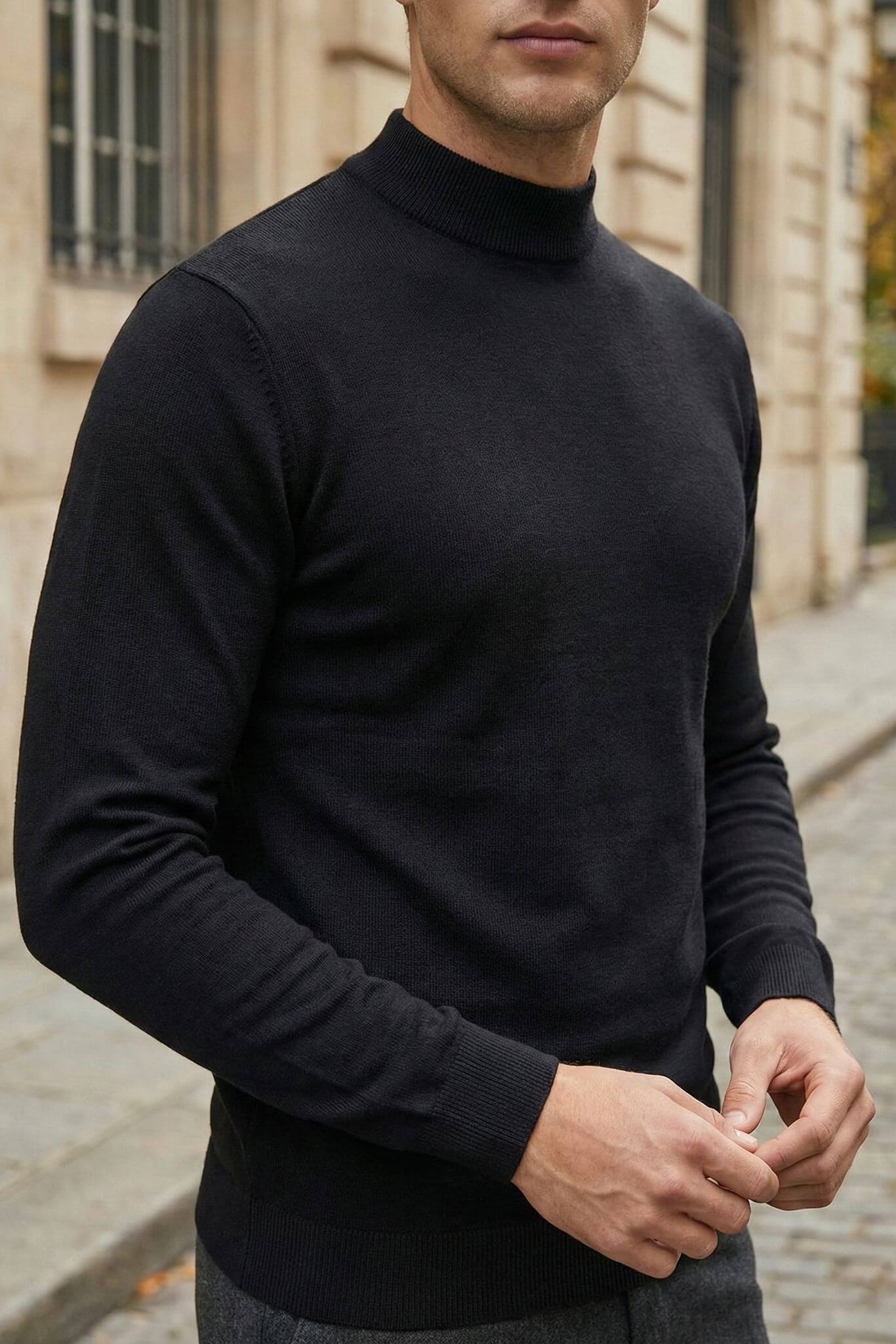 Man wearing a black turtleneck sweater standing outdoors.