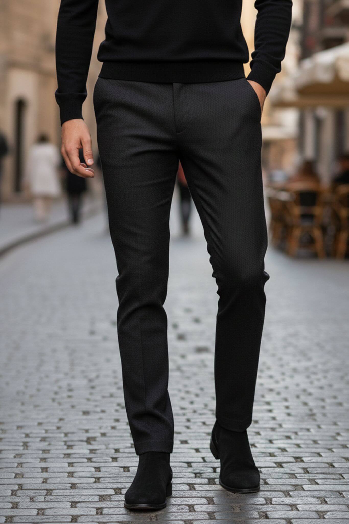 Person wearing black pants and shoes on a cobblestone street.