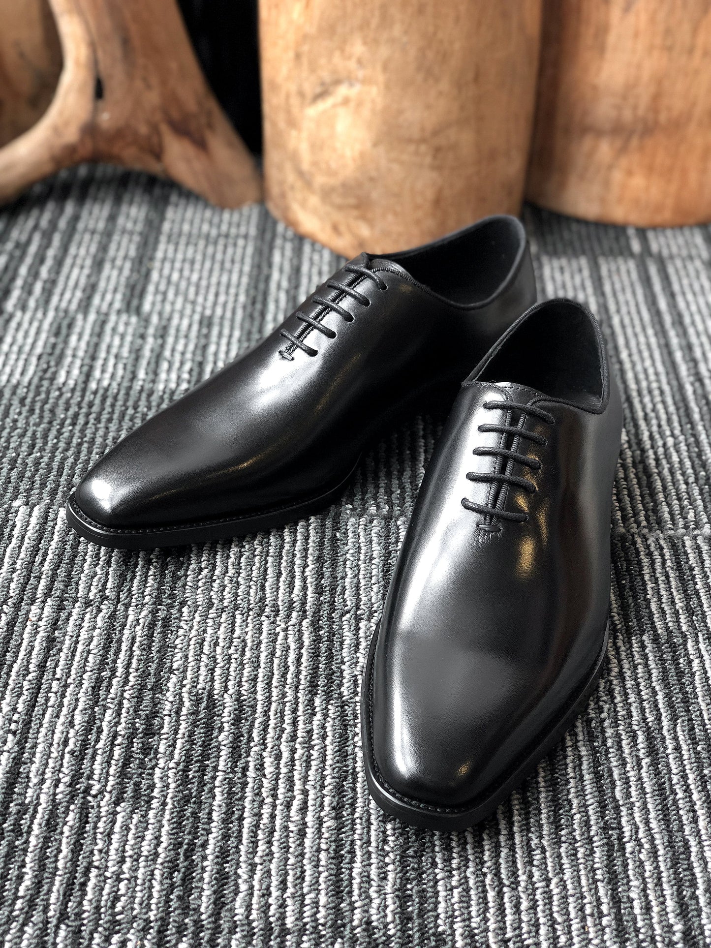 A pair of sleek Black Leather Oxford Shoes, featuring a polished finish, ideal for formal wear and business attire.