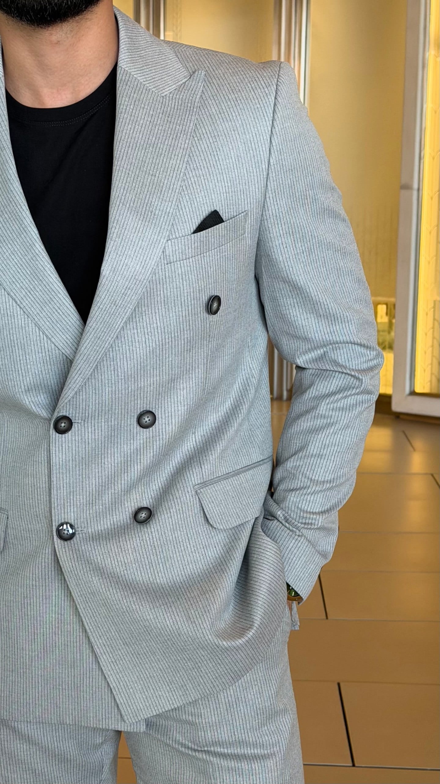 Men's light gray double-breasted suit from an angled view