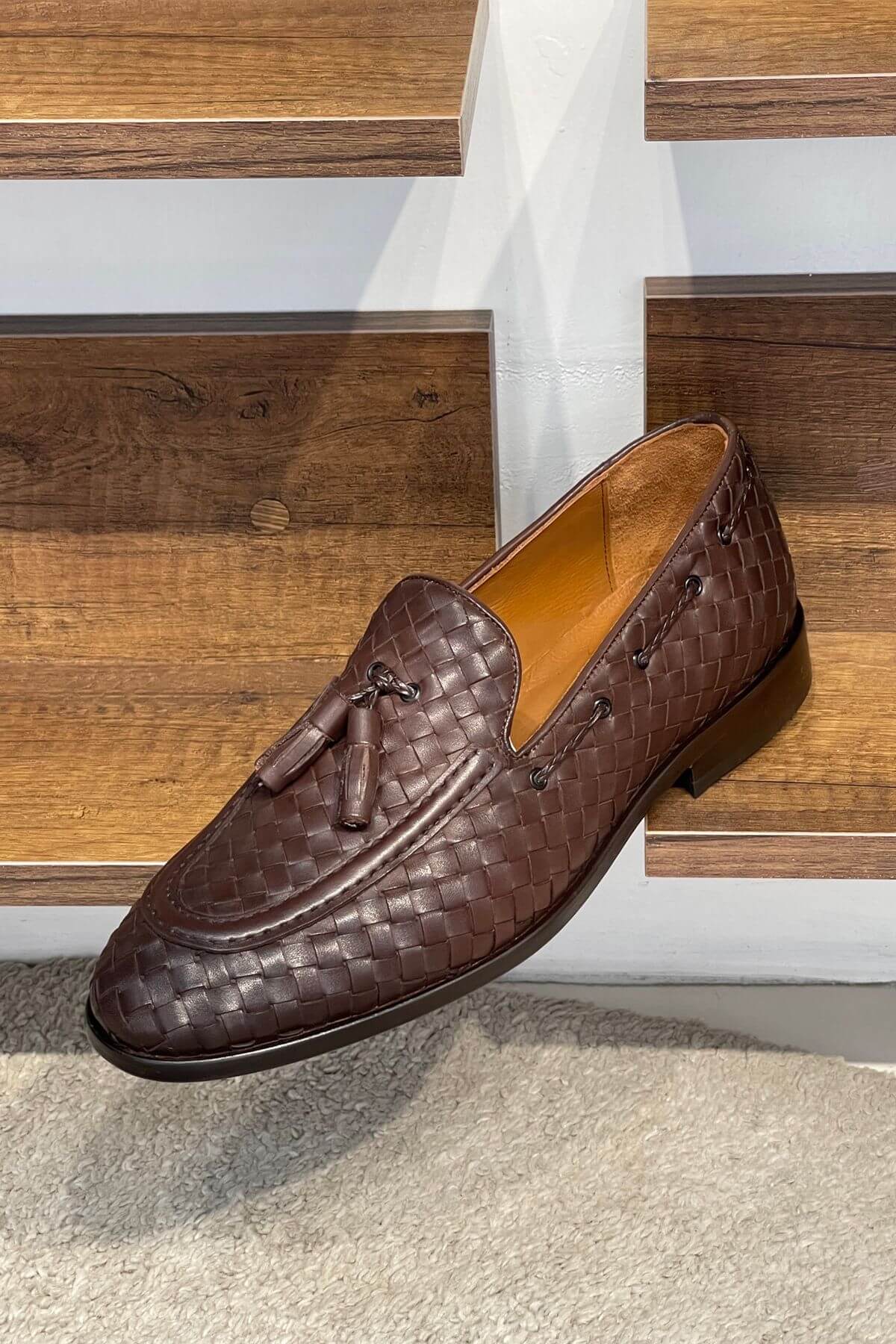 Brown woven loafer shoe on a wooden staircase