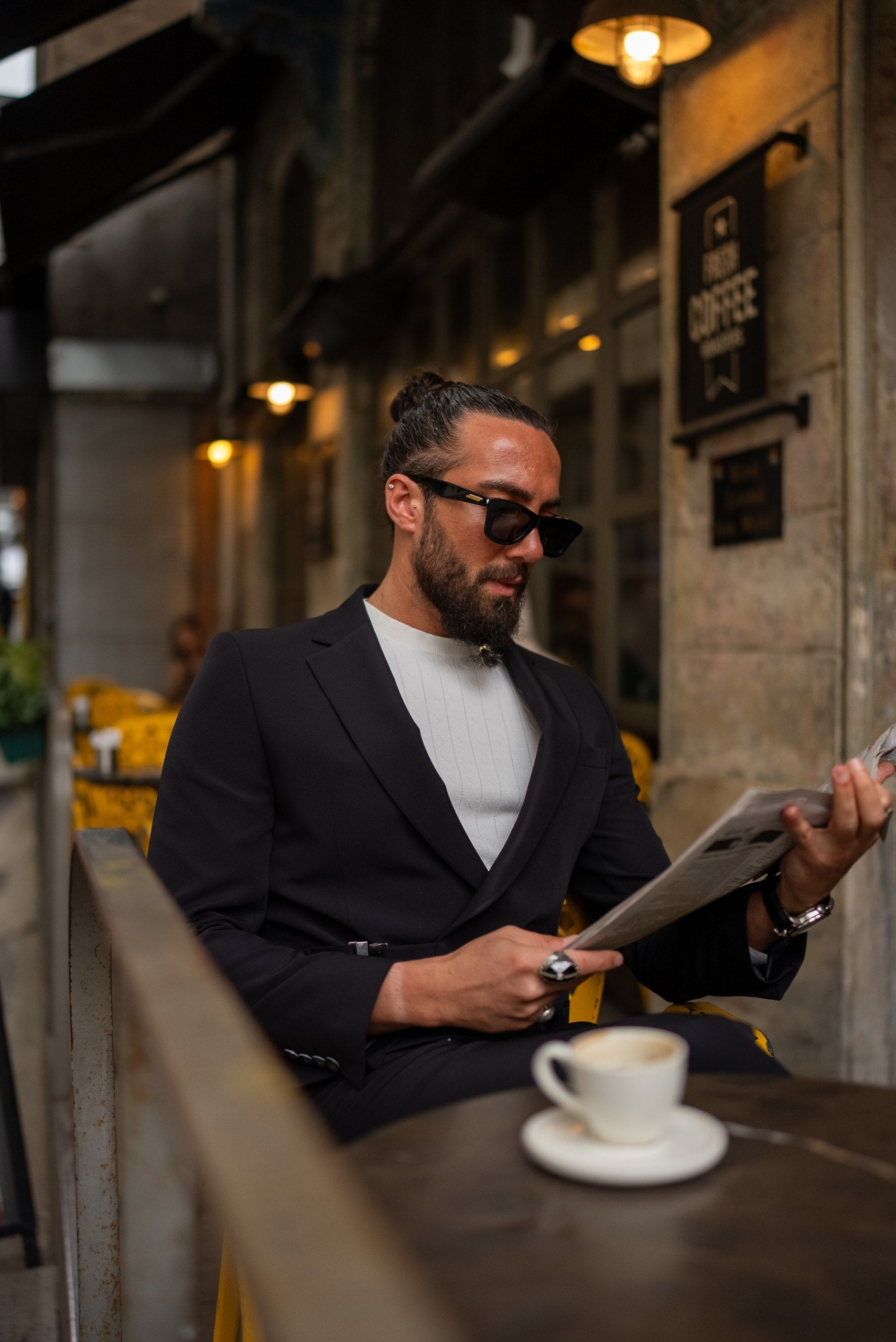 Stylish groom wearing black slim-fit suit with buckle detail, street style
