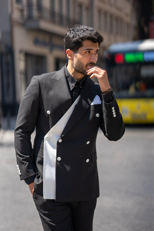 Man in a black suit with white accents walking on a city street.