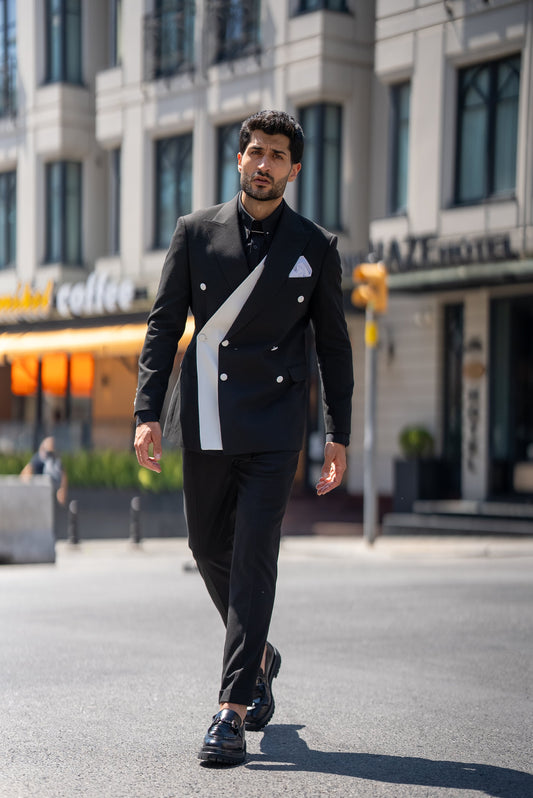 Man in a stylish black suit walking on a city street.