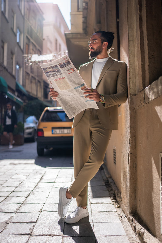 Man wearing a camel textured summer suit reading a newspaper, slim fit blazer with tapered trousers
