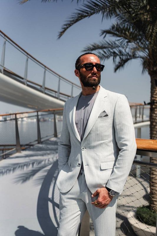 Stylish man wearing gray suit jacket and trousers, paired with sunglasses
