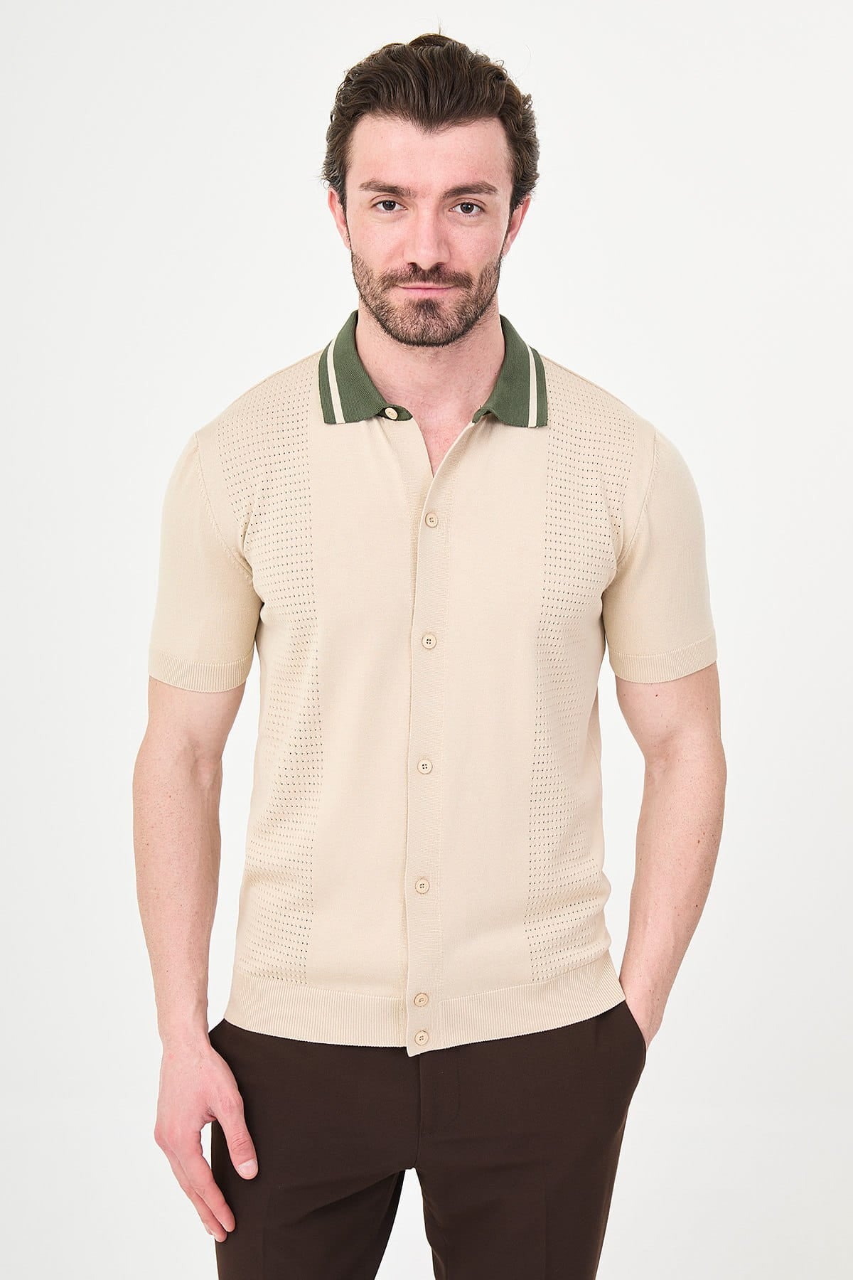 Man wearing a beige short-sleeve shirt with green trim on a white background