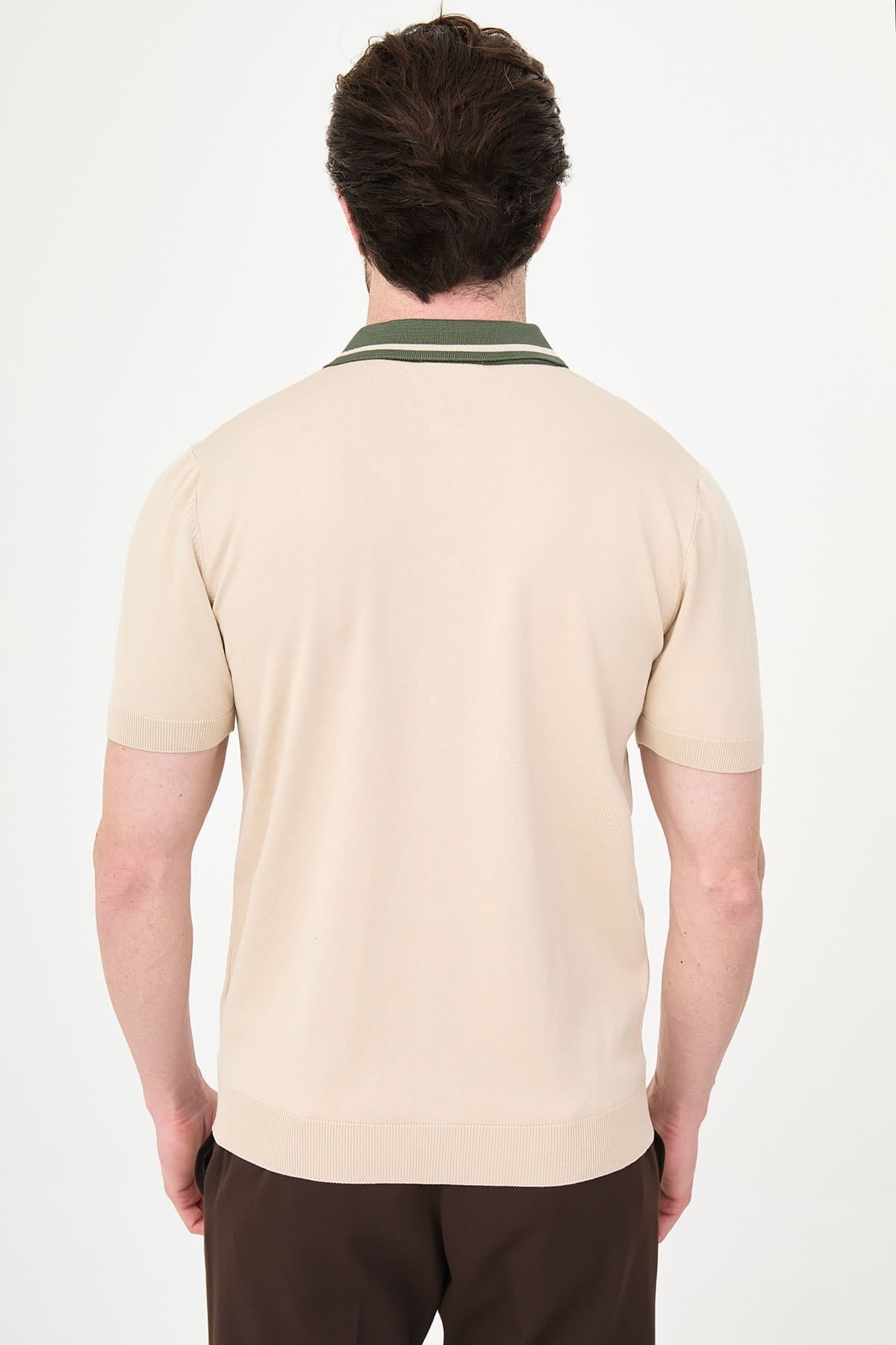 Man wearing a beige polo shirt with a green collar on a white background