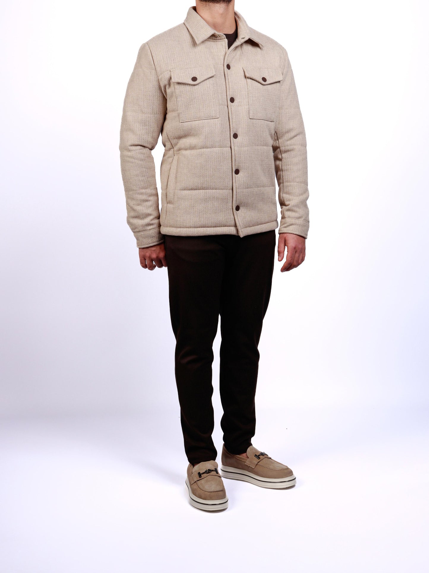 Person wearing a beige quilted jacket on a white background