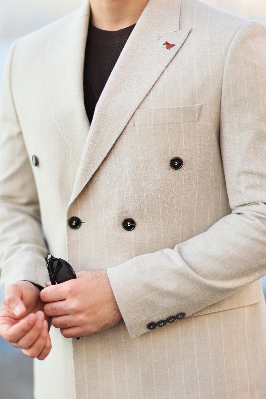 Beige double-breasted suit jacket with black buttons on a blurred background