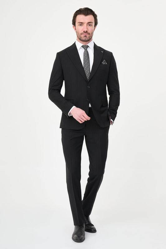 Man wearing a black suit with a white shirt and patterned tie on a white background