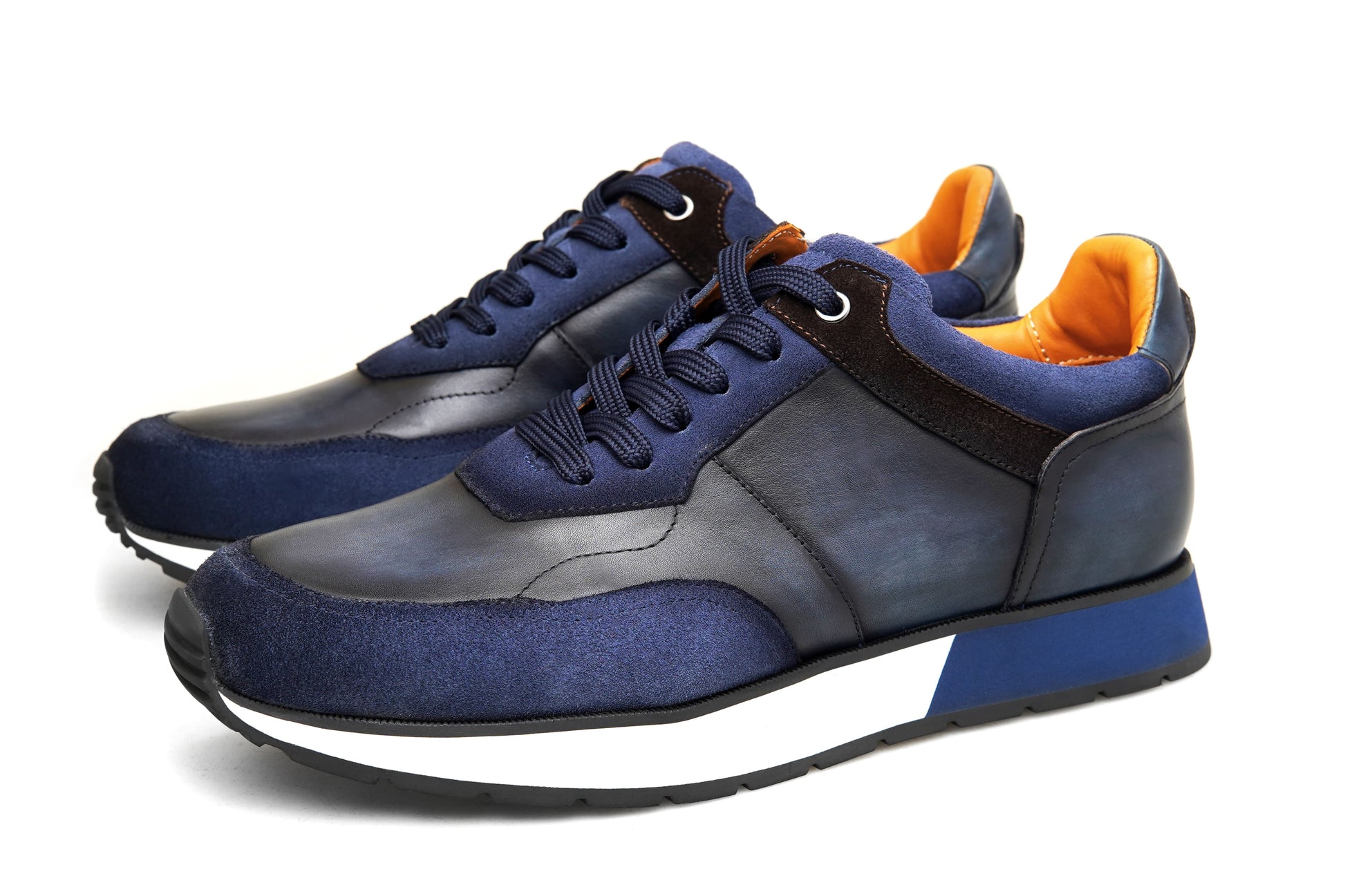 Blue and black sneakers with orange lining on a white background