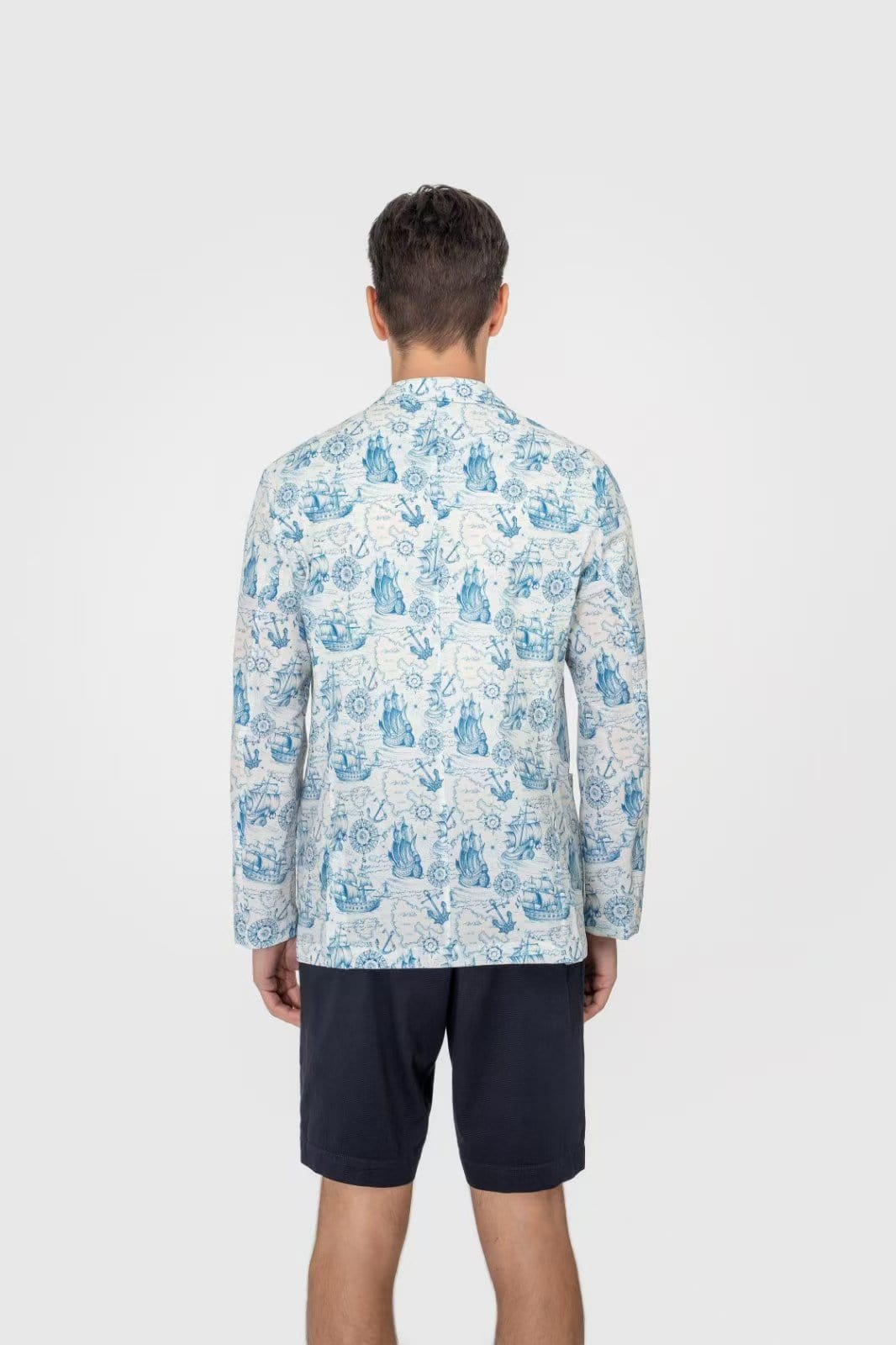 Man wearing a patterned shirt and shorts on a white background
