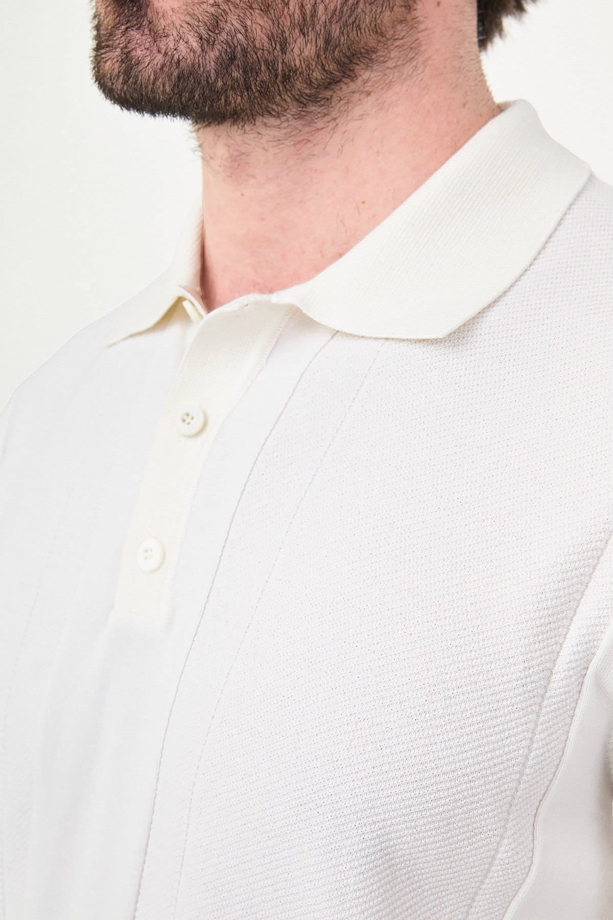 Close-up of a person wearing a white textured shirt with a collar.