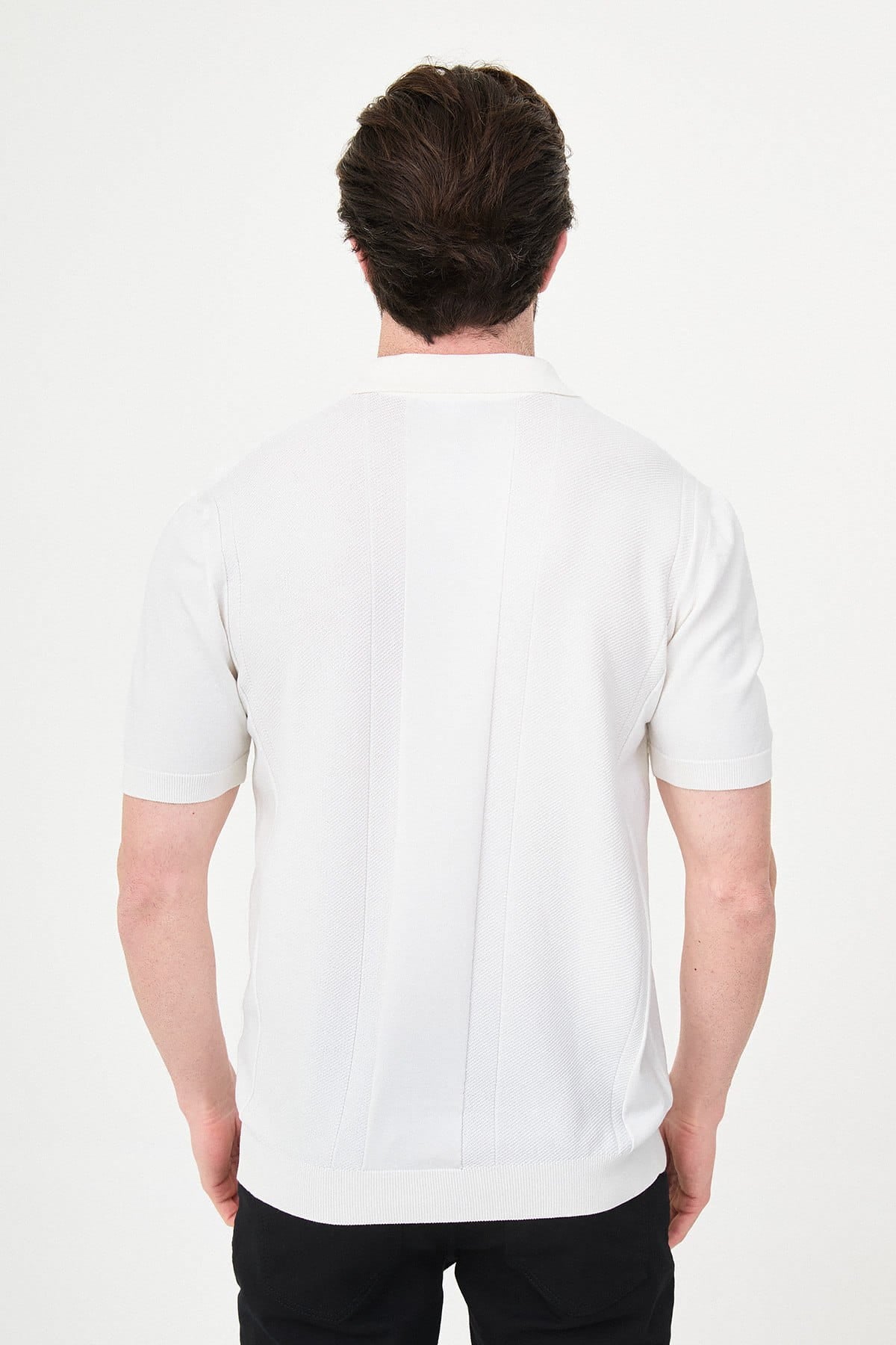 Person wearing a white polo shirt on a plain background