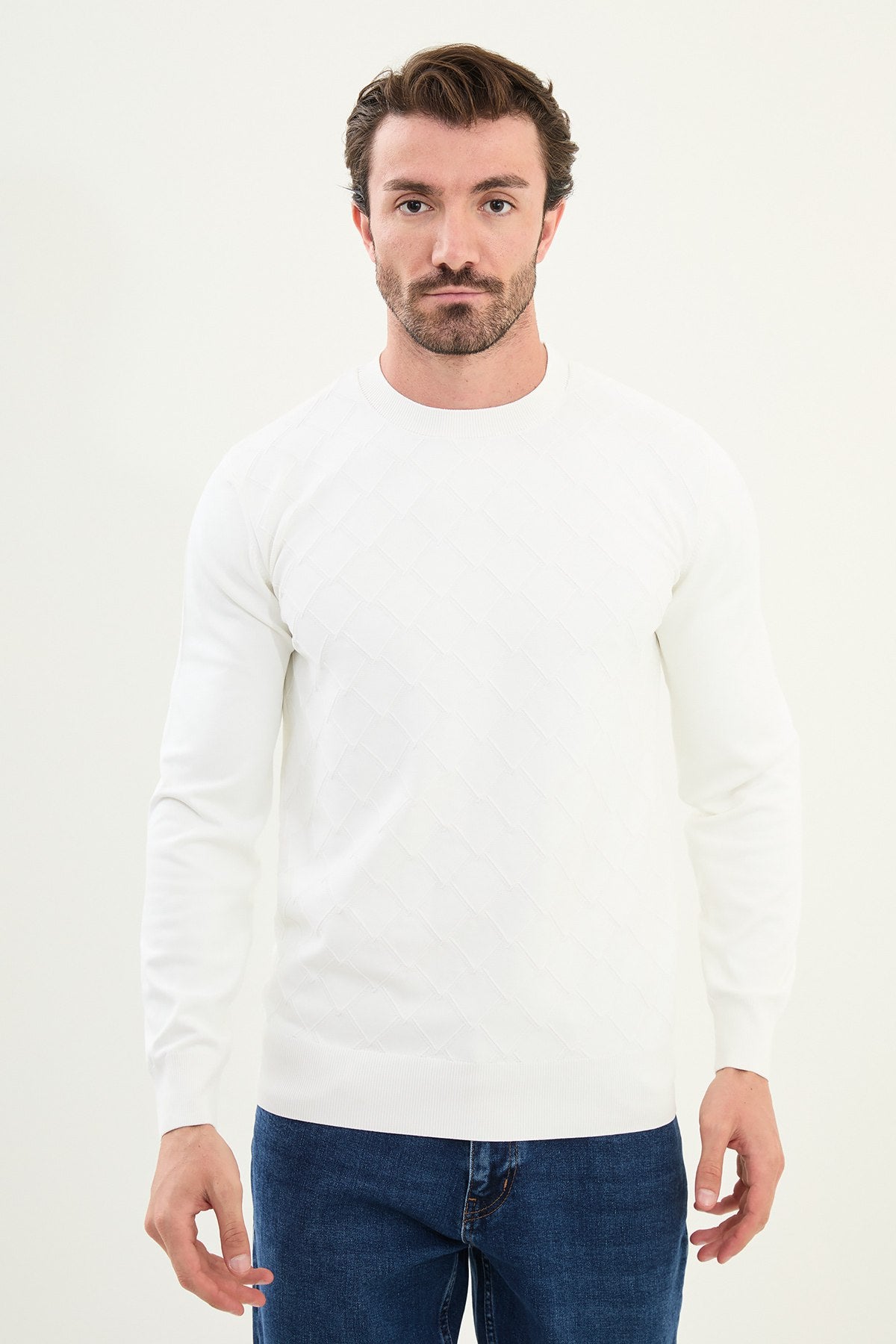 Man wearing a white long-sleeve shirt and blue jeans on a white background
