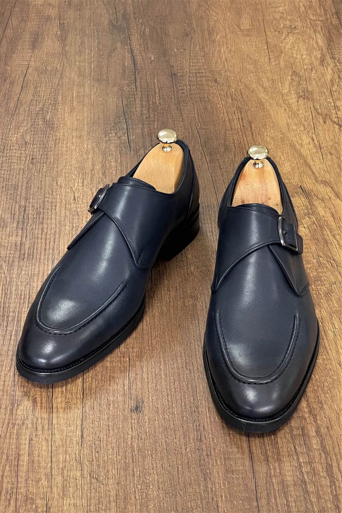 Pair of black leather shoes on a wooden surface
