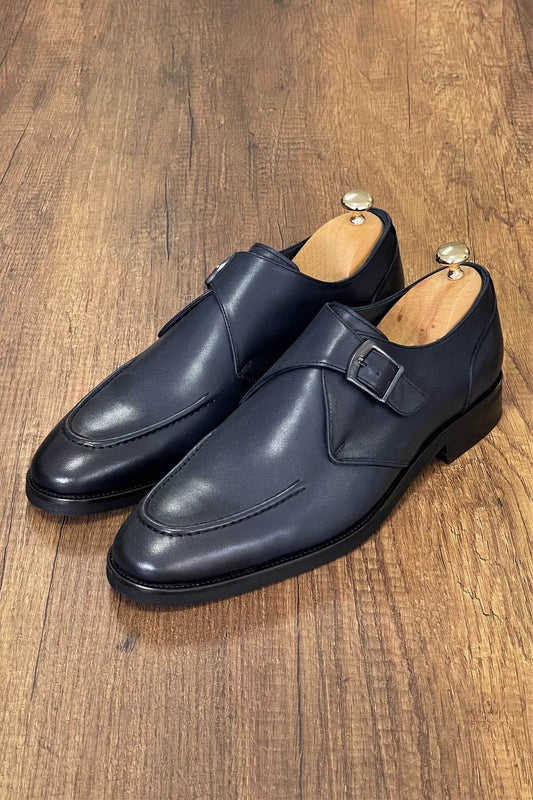 Pair of navy blue monk shoes on a wooden surface