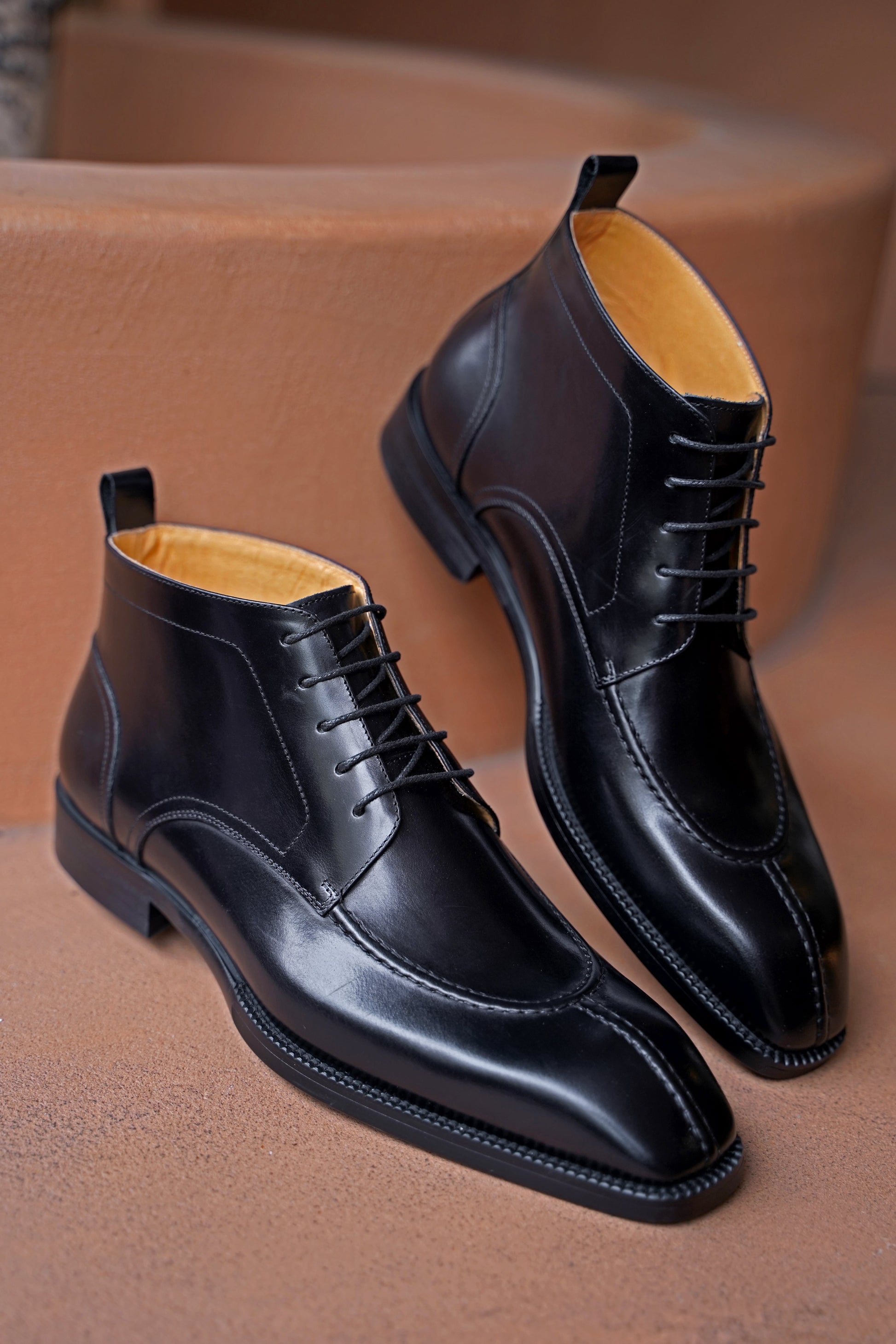 A pair of sleek black leather lace-up boots, featuring a polished finish and elegant design, ideal for formal wear and business attire.