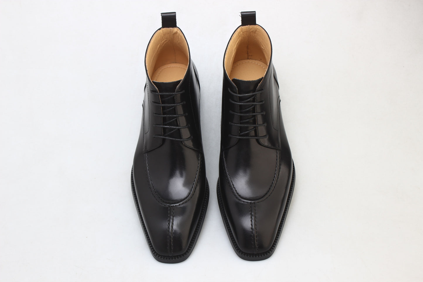 A pair of sleek black leather lace-up boots, featuring a polished finish and elegant design, ideal for formal wear and business attire.