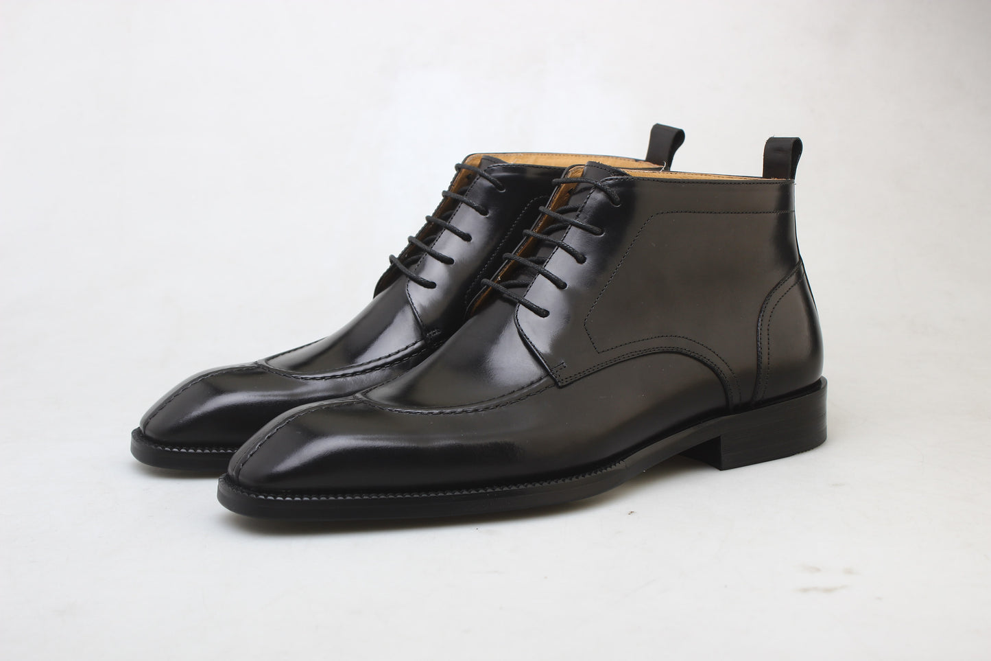 A pair of sleek black leather lace-up boots, featuring a polished finish and elegant design, ideal for formal wear and business attire.