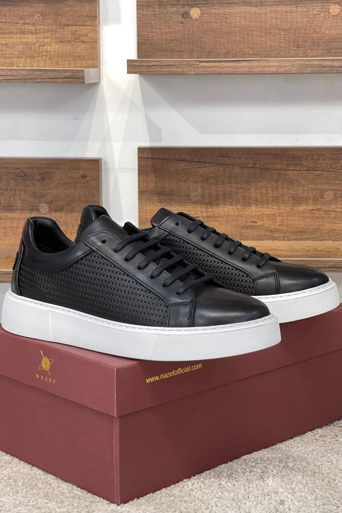 Black sneakers with white soles on a red box against a wooden background