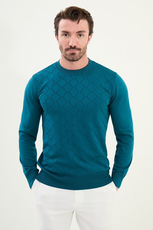 Man wearing a teal diamond patterned sweater against a white background
