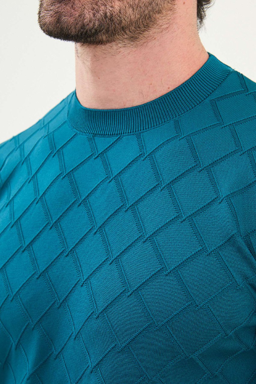 Teal patterned sweater worn by a person on a light background