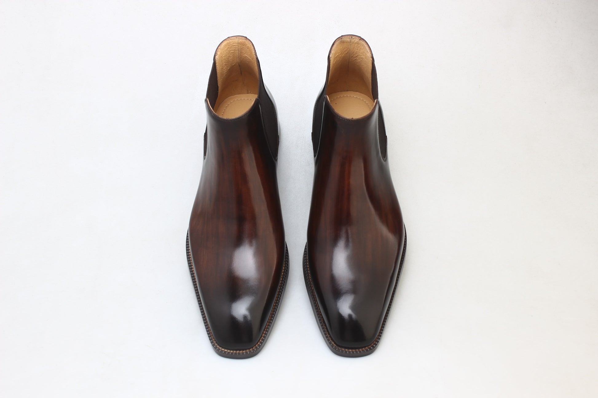 A pair of polished brown leather Chelsea boots, featuring a sleek design, perfect for formal and business wear.