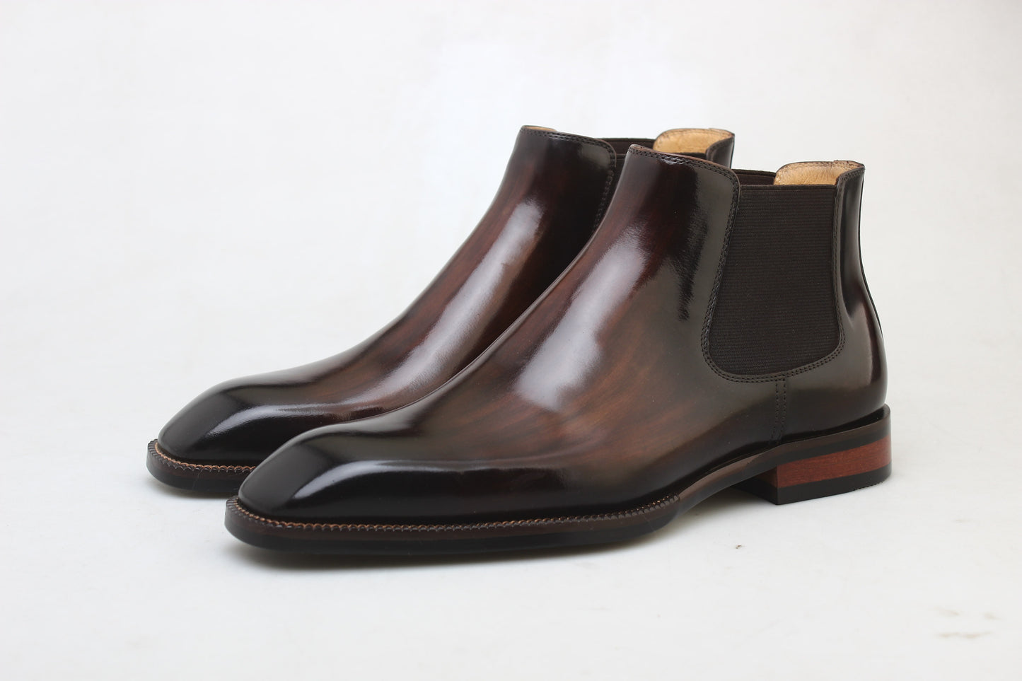 A pair of polished brown leather Chelsea boots, featuring a sleek design, perfect for formal and business wear.