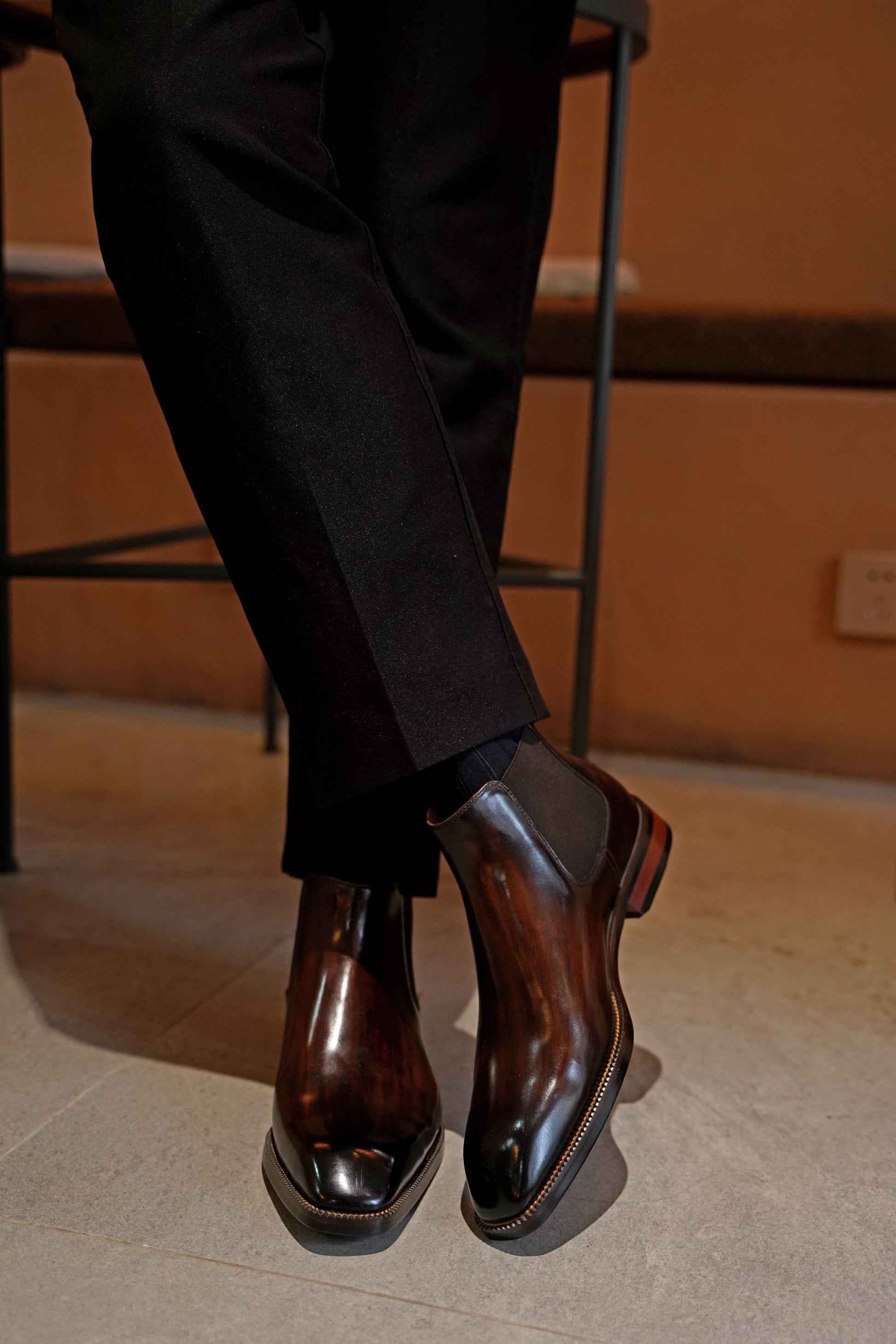 A pair of polished brown leather Chelsea boots, featuring a sleek design, perfect for formal and business wear.