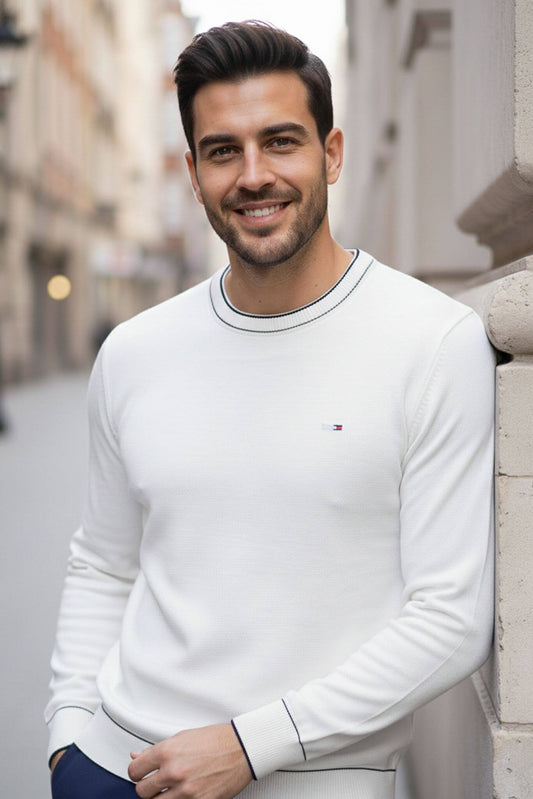 Man wearing a Slim-fit Crew Neck Sweater with Contrast Piping in White with a brand logo, standing on a street.