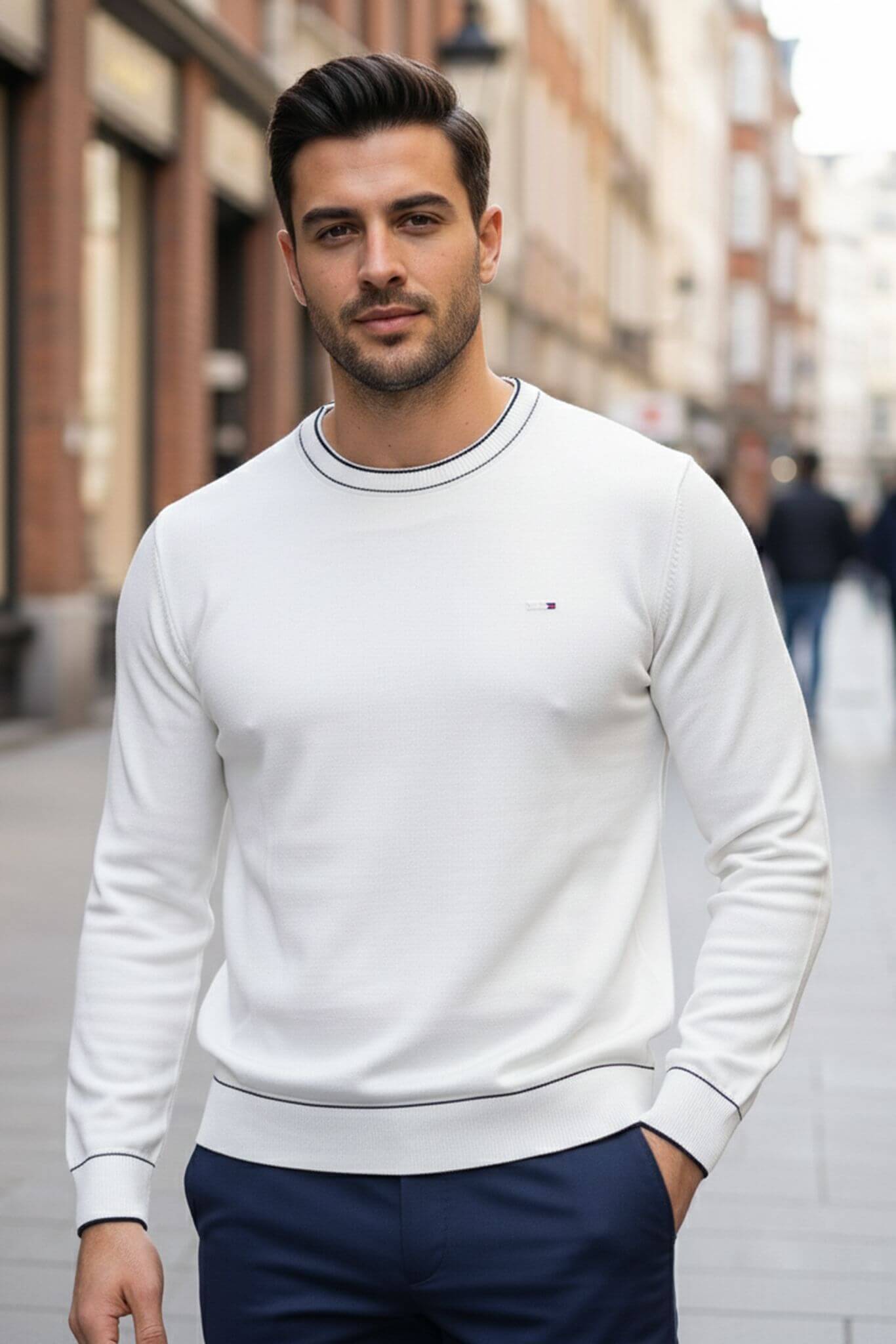Man wearing a Slim-fit Crew Neck Sweater with Contrast Piping in White with a small logo on a city street