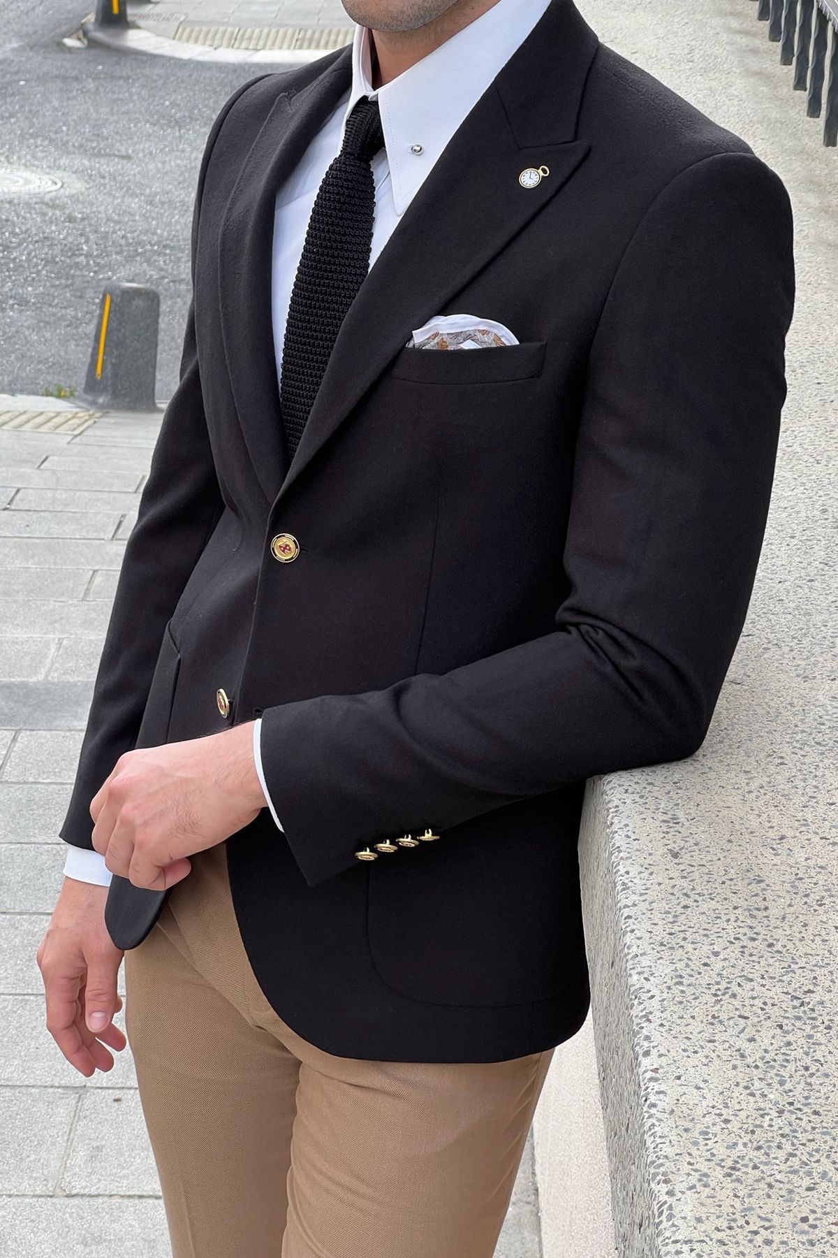 Person wearing a black blazer, white shirt, and beige pants with a pocket square.