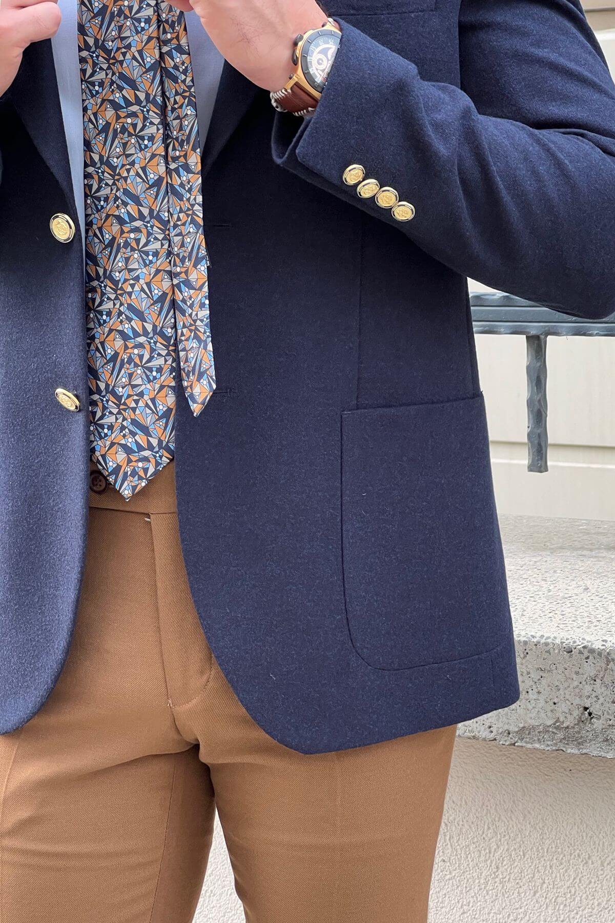 Slim-fit Gold-Buttoned Wool Blend Blazer in Navy Blue ,patterned tie, and beige pants.