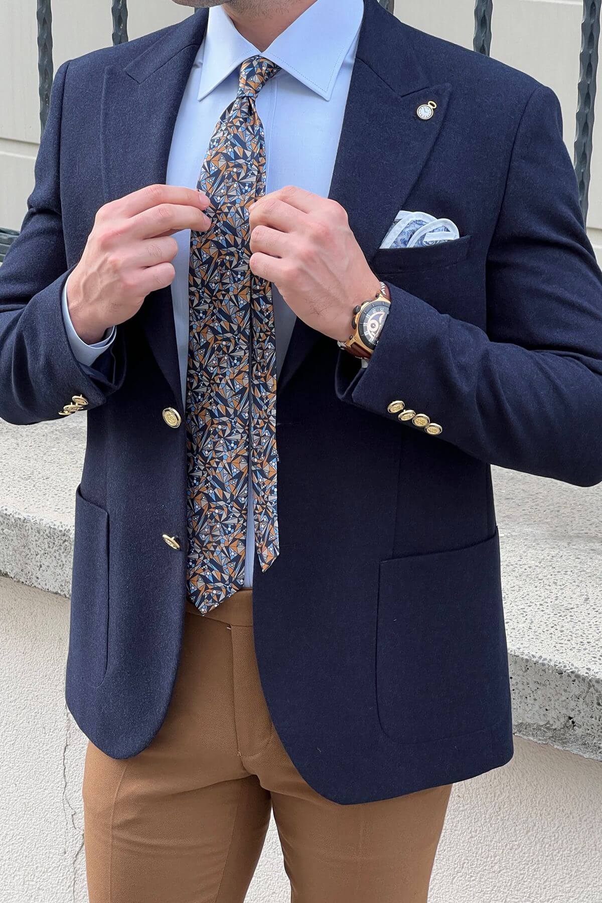 Man adjusting a patterned tie against a neutral background