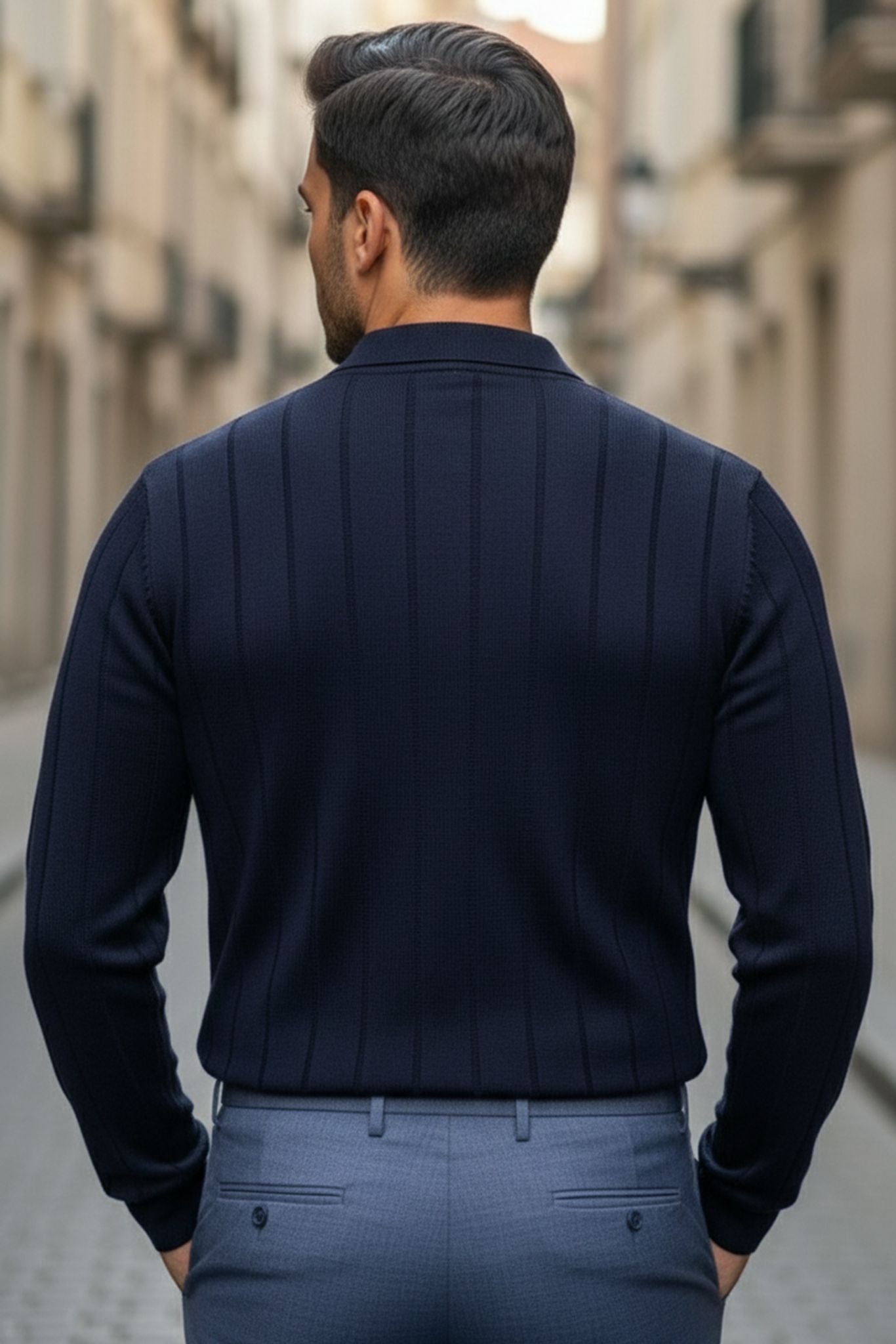 Man wearing a Slim-fit Ribbed Knitted Polo Sweater in Navy Blue and light blue pants walking down a street.