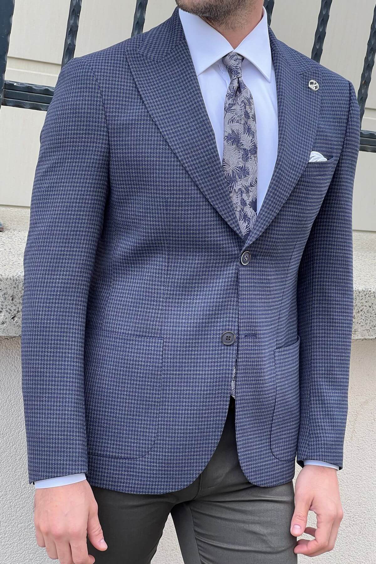 Man wearing a blue checkered suit jacket with a light blue shirt and patterned tie.