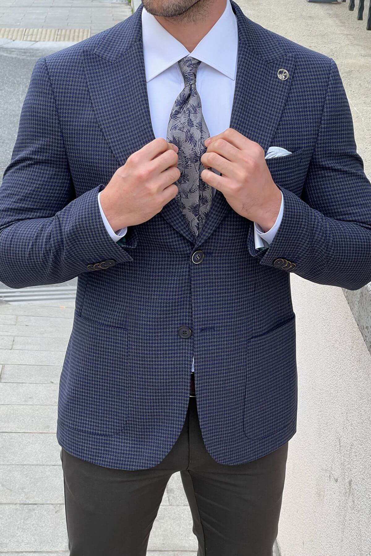 Man adjusting his tie in a blue checkered suit with a white shirt.