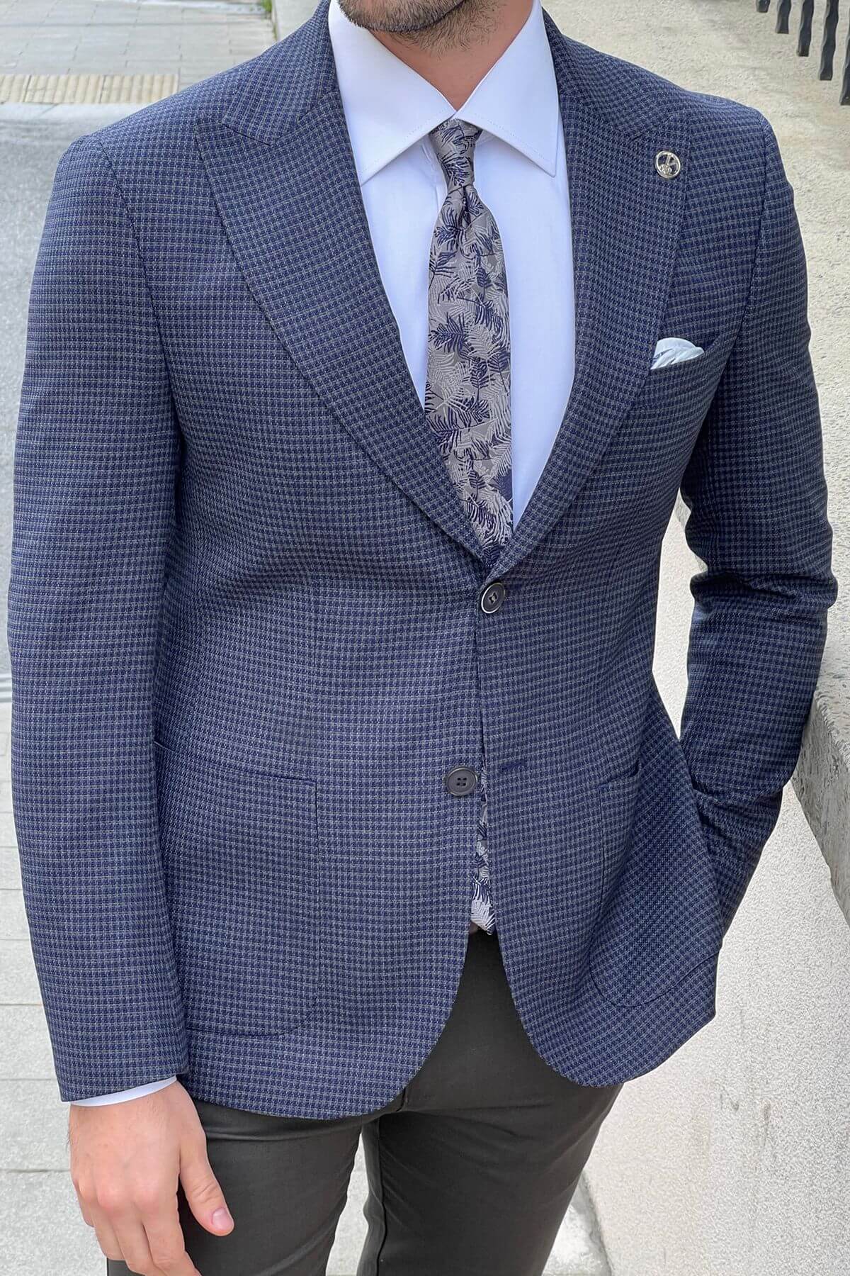 Man wearing a blue checkered suit with a floral tie against a light background