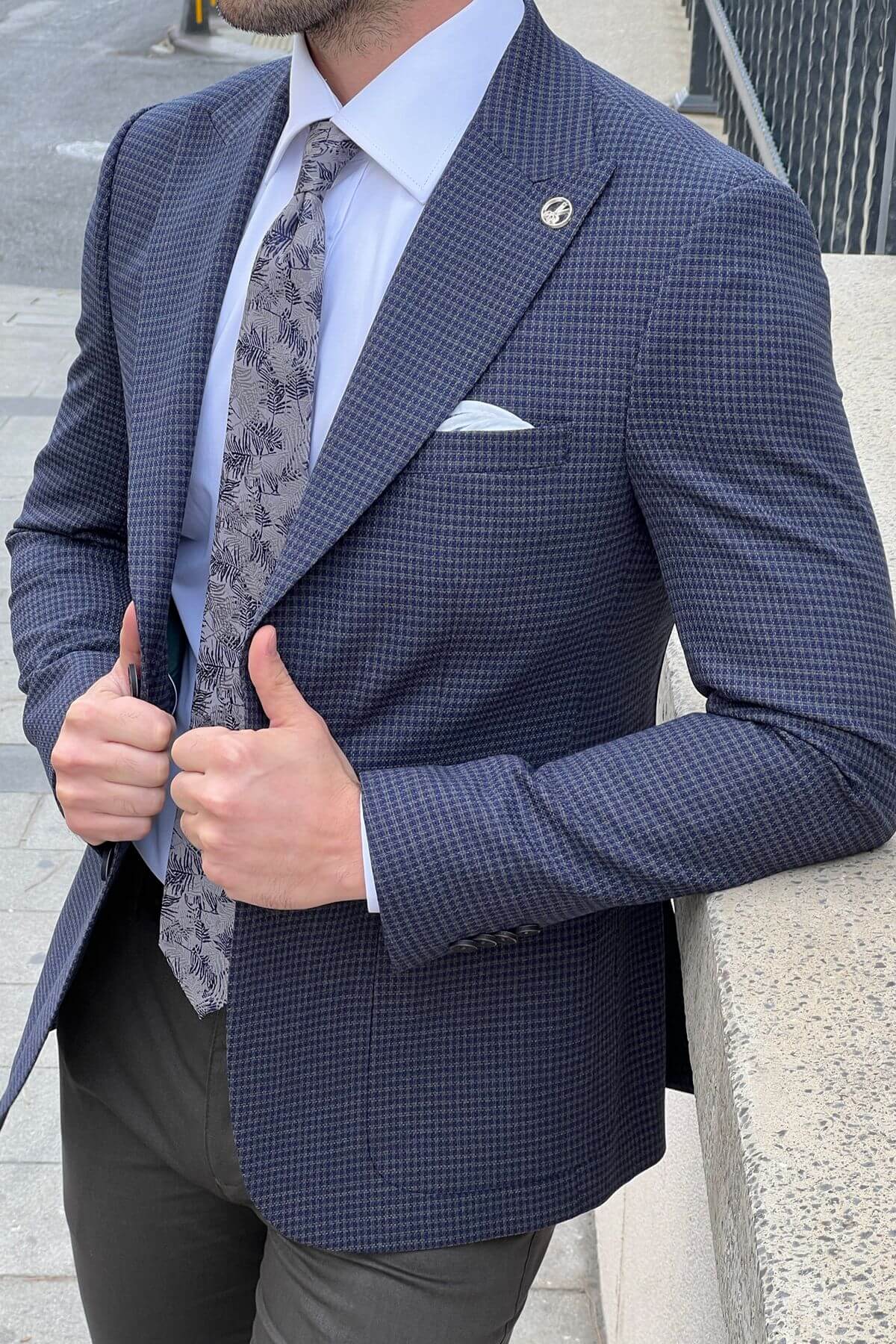 Man wearing a blue checkered suit with a patterned tie and pocket square.